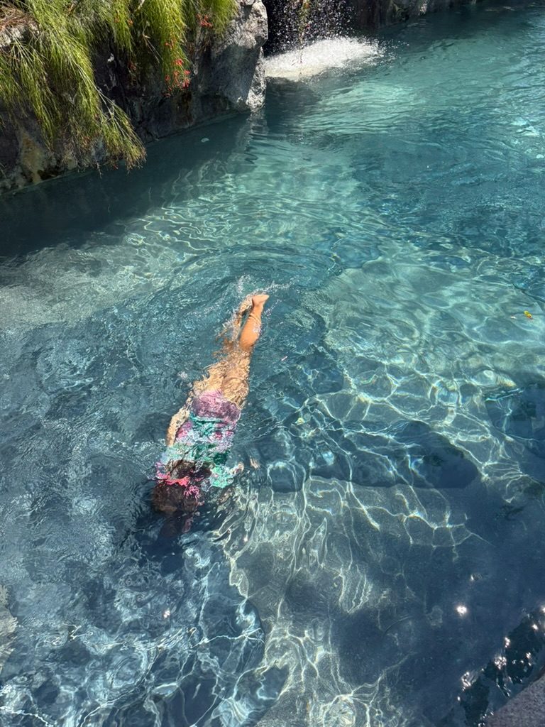 A child diving through the crystal-clear water of the hotel's natural rock-cut cave pool