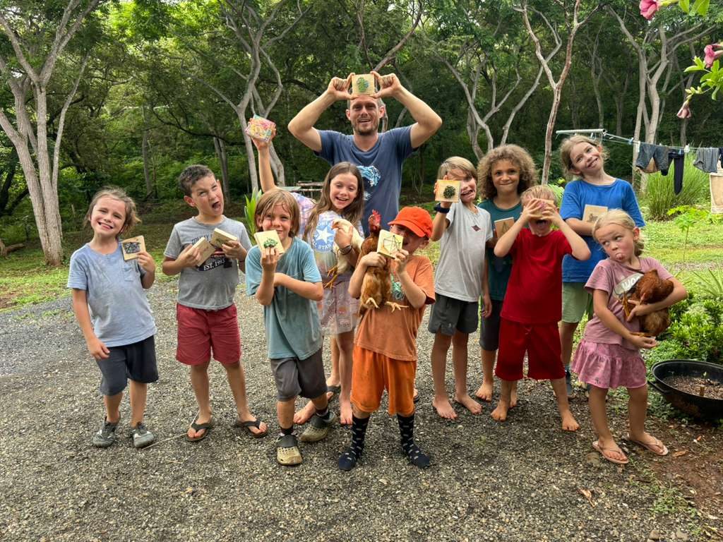 A big group of children holding their hand-made nature crafts and a hen at a local school